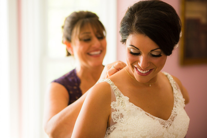 mom putting bride's necklace on before Syracuse wedding