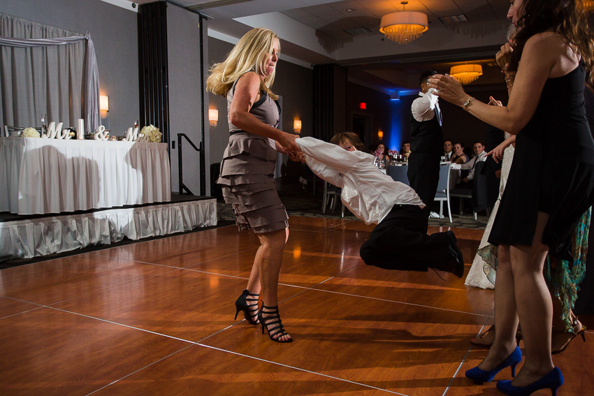 mom swinging son at wedding reception