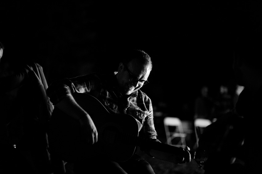 groom playing guitar by the bonfire