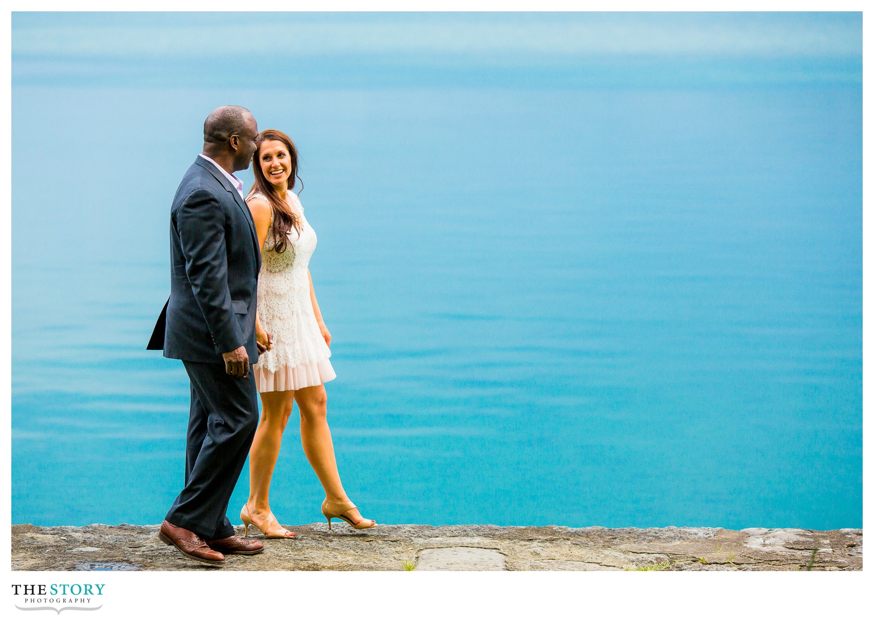 engaged couple walking along Skaneateles Lake