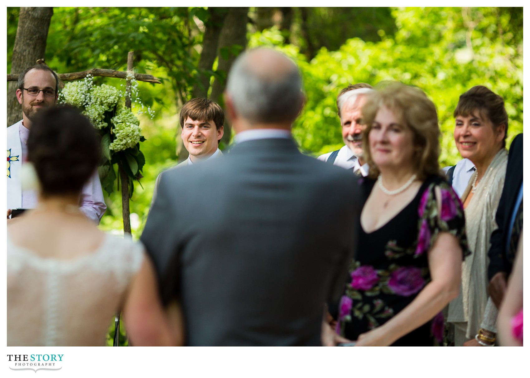 groom watches bride walk down the aisle for creekside wedding ceremony