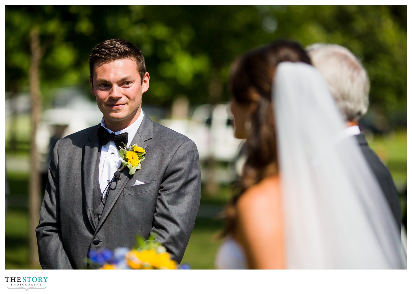 groom sneaking a glance at his bride at wedding ceremony on Wellesley Island