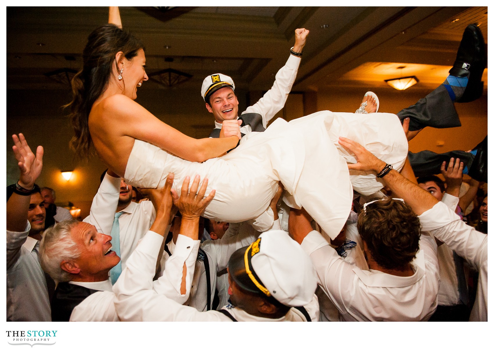 friends and family lift up bride and groom at wedding reception