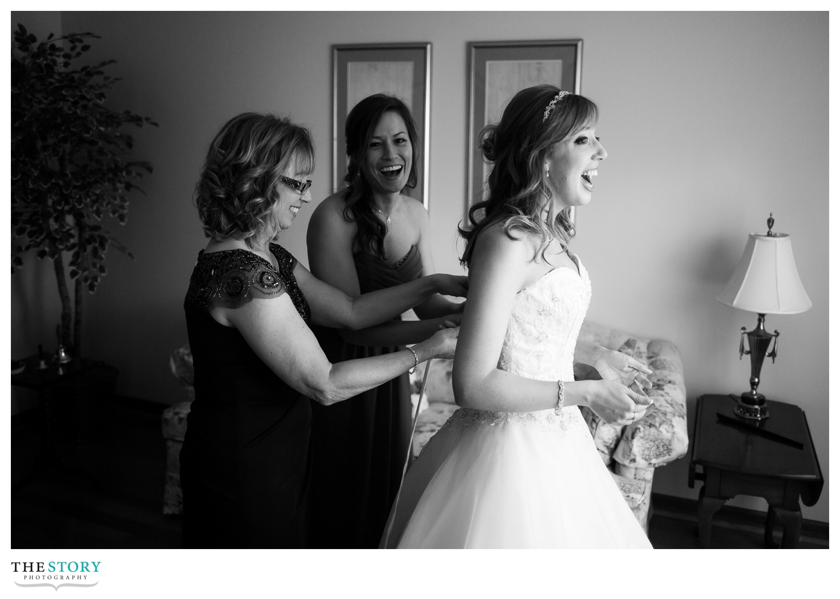bride getting wedding dress on with her mother and maid of honor