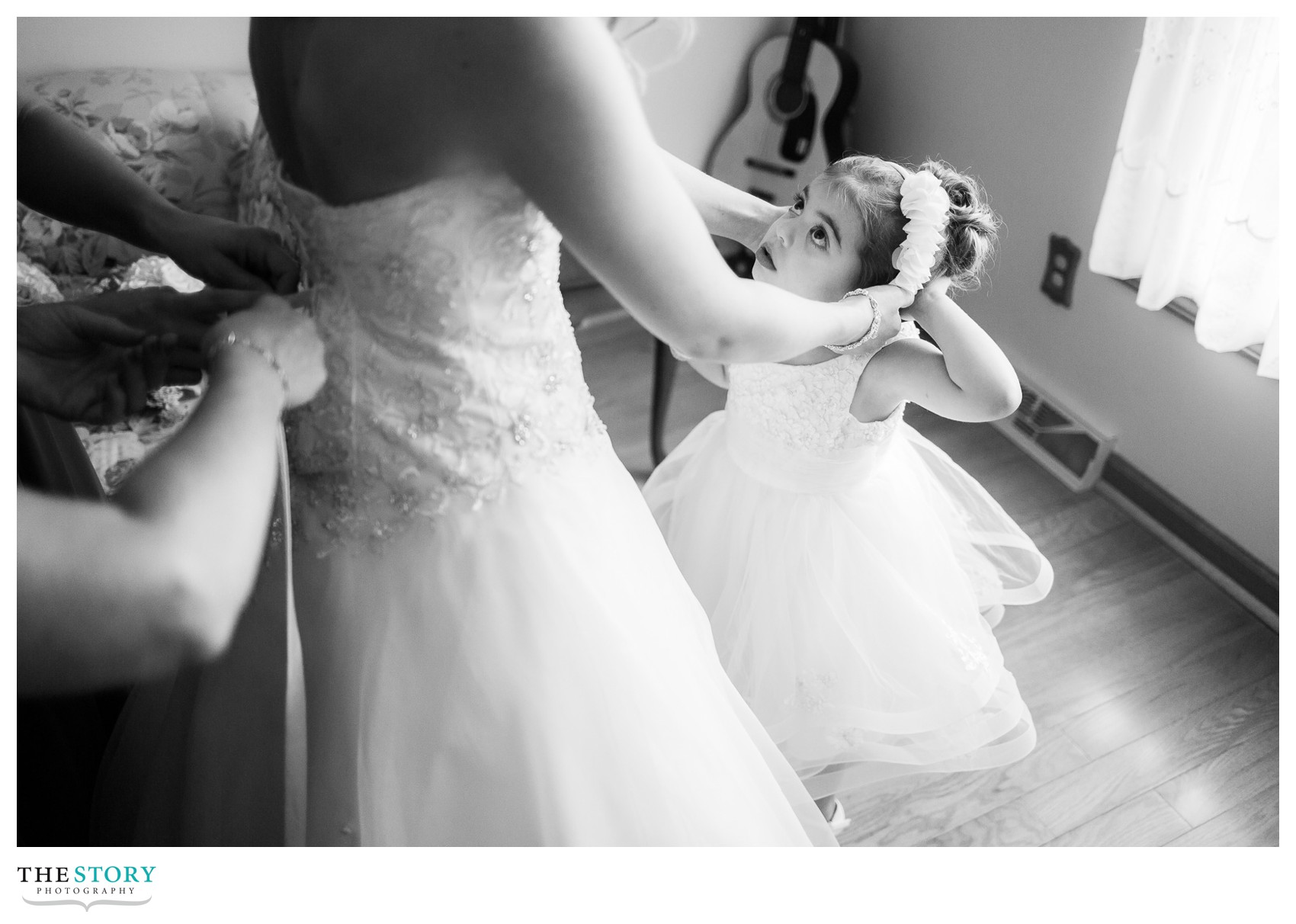 flower girl looking up to bride getting her dress on