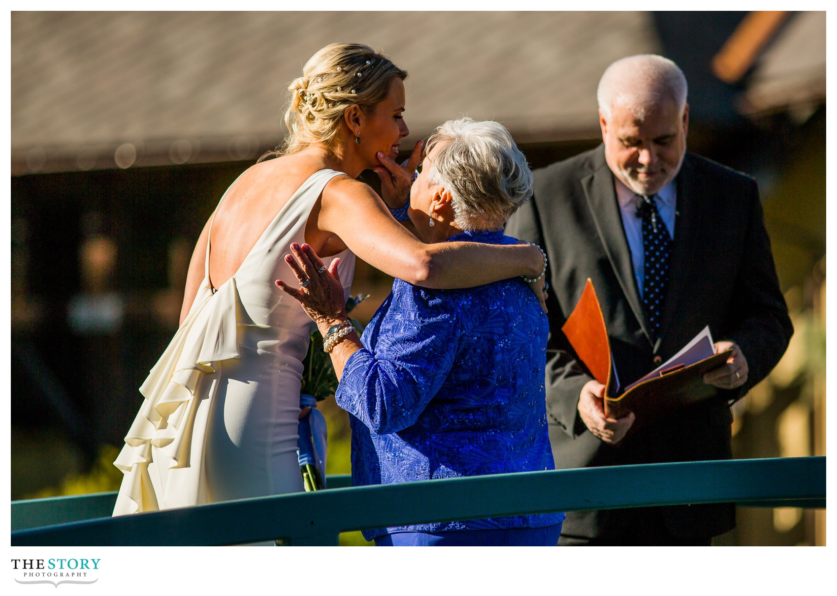 bride's mother wipe lipstick from her cheek at wedding ceremony on mirbeau bridge