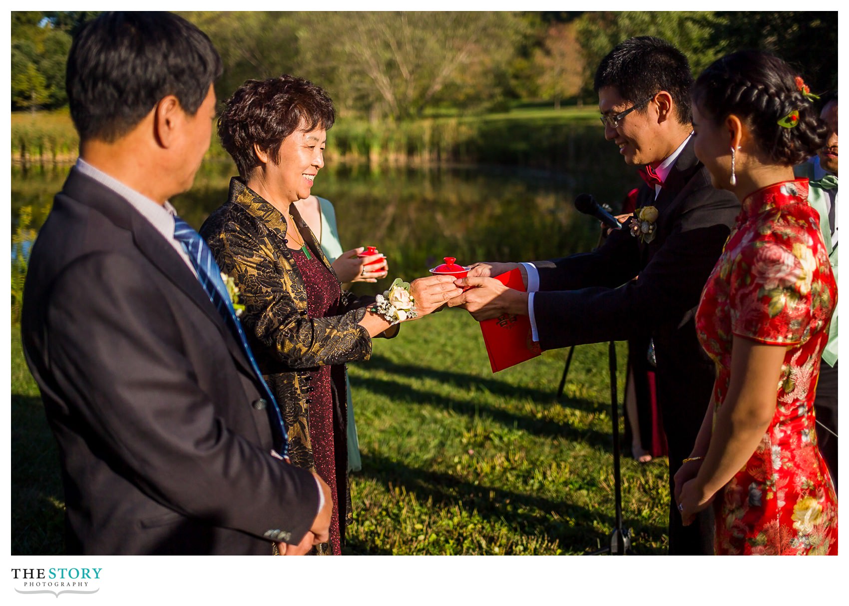 groom serves tea to the bride's mother during Chinese wedding tea ceremony at Cornell Plantations