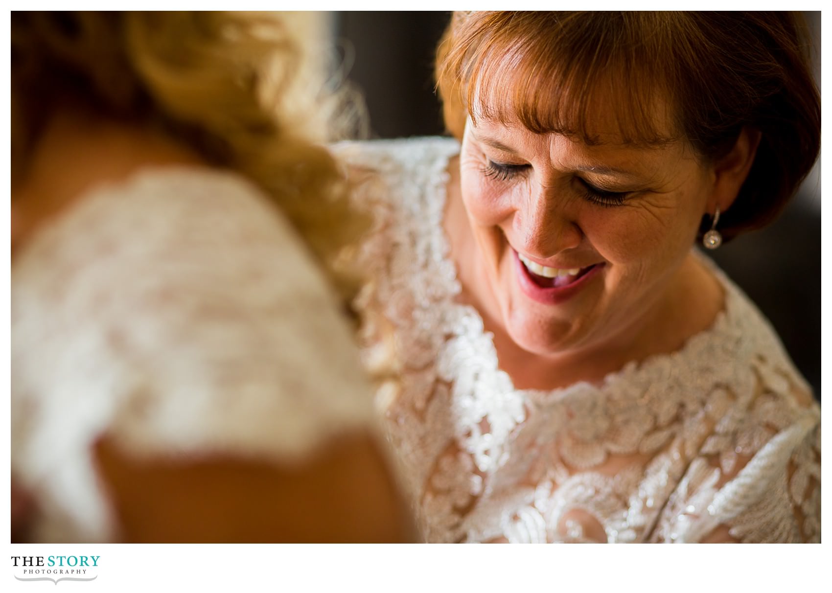 mother helping bride with dress before wedding ceremony in Syracuse