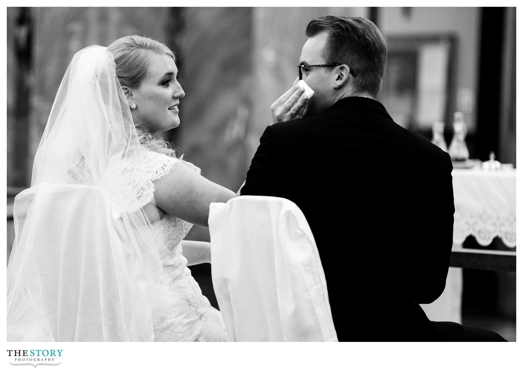 bride wipes groom's face during Sacred Heart wedding ceremony in Syracuse