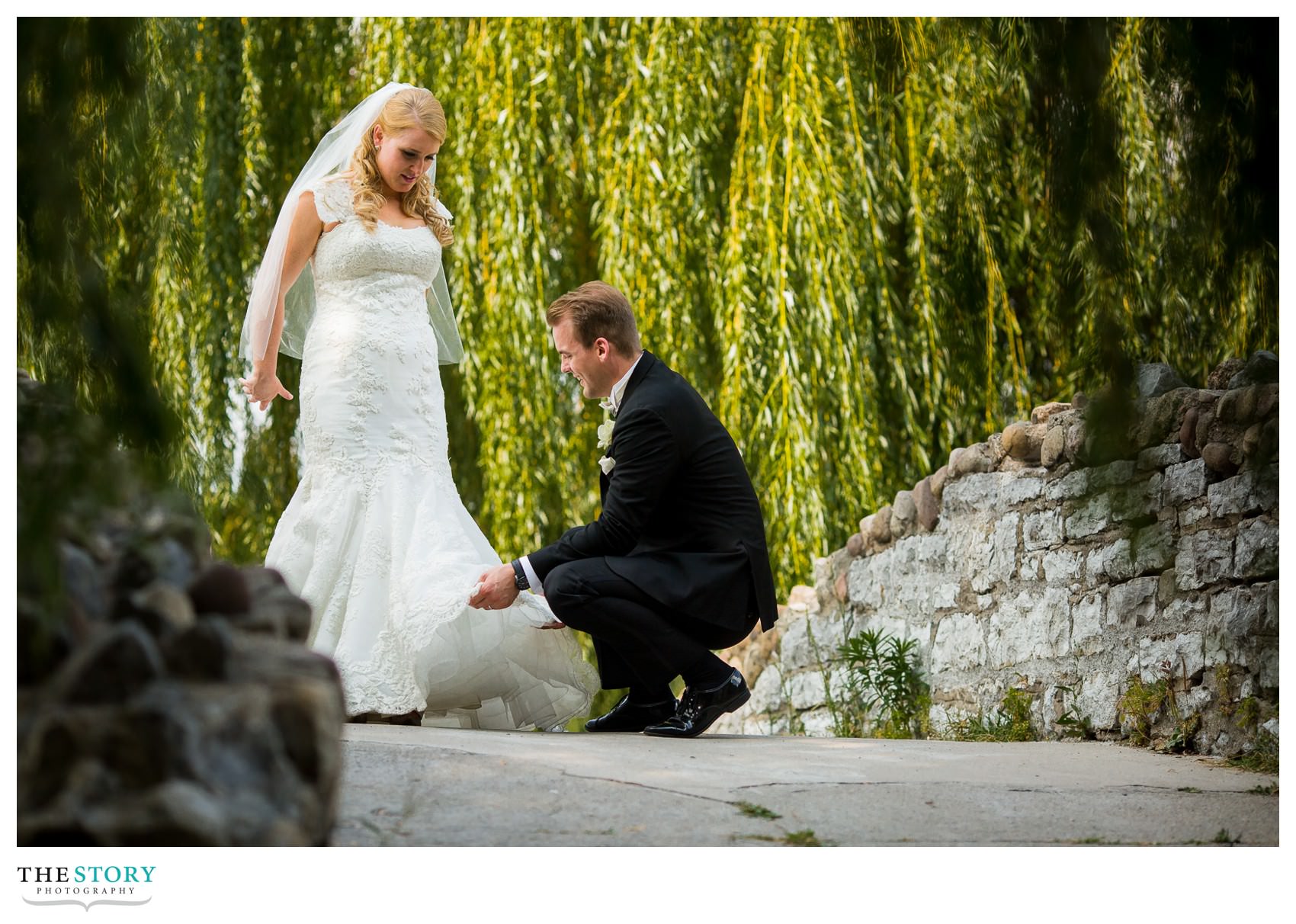 Groom fixing bride's wedding dress