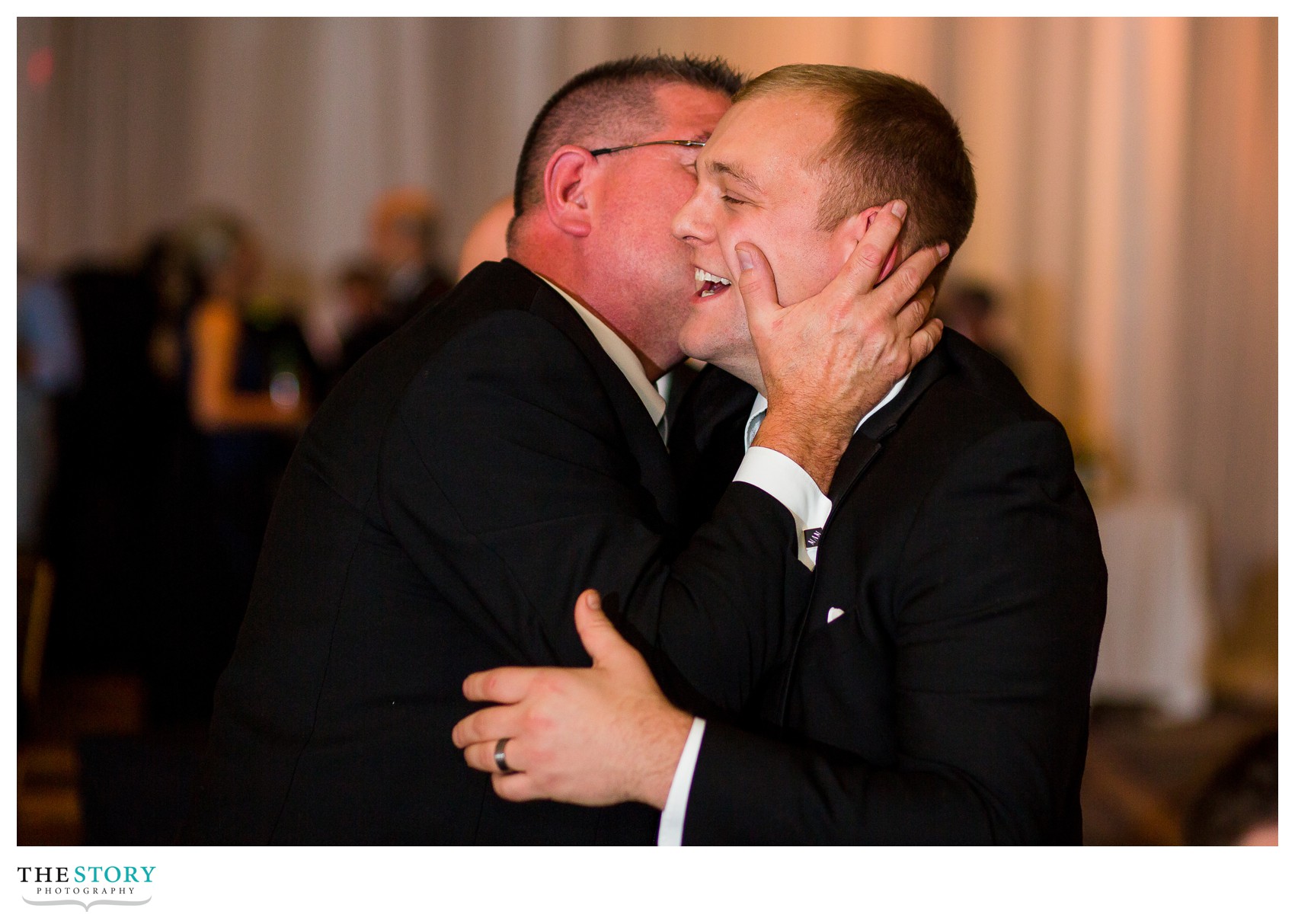 bride's father embraces groom during
 wedding reception