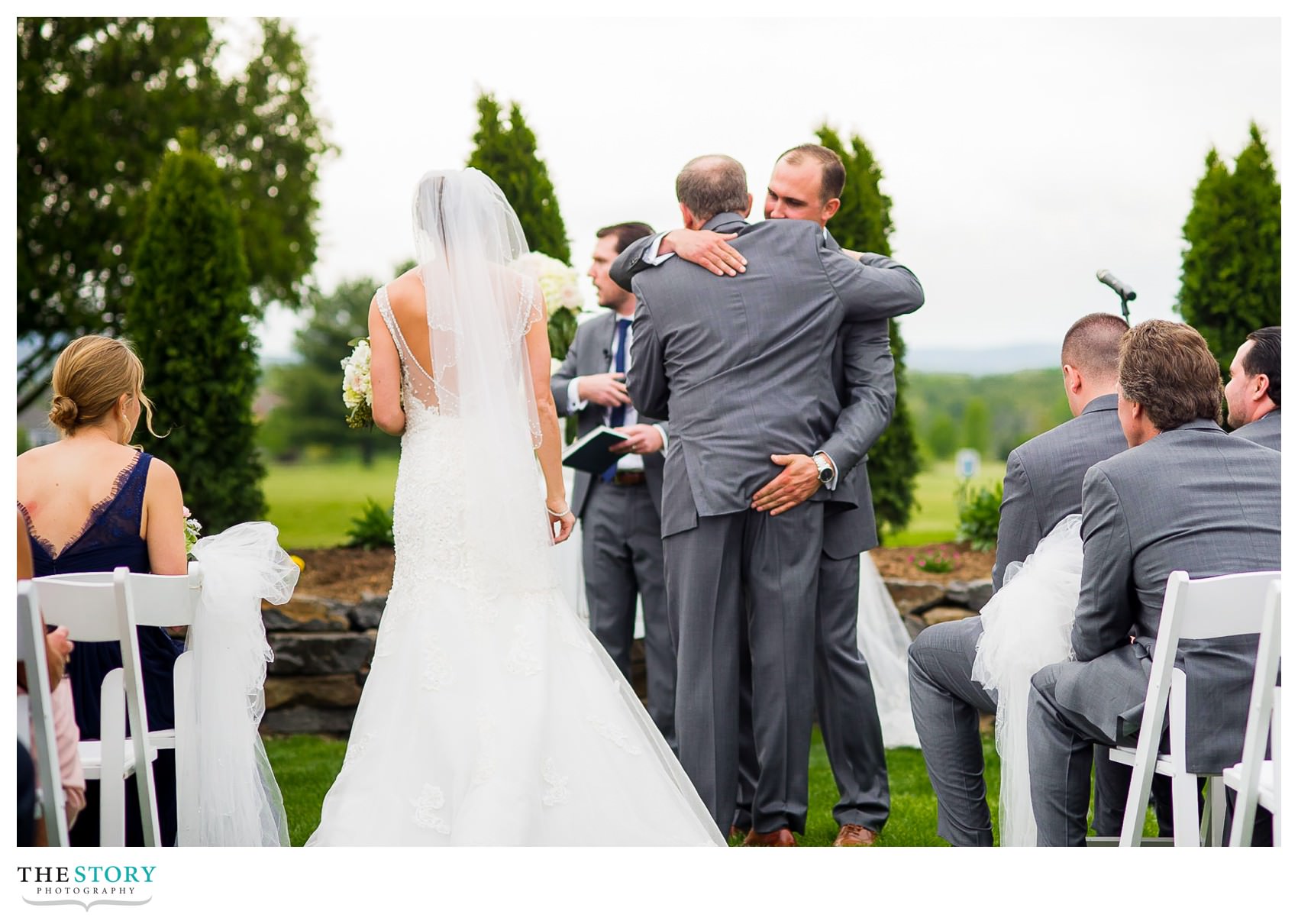 groom pats the bride's father on the butt at wedding ceremony
