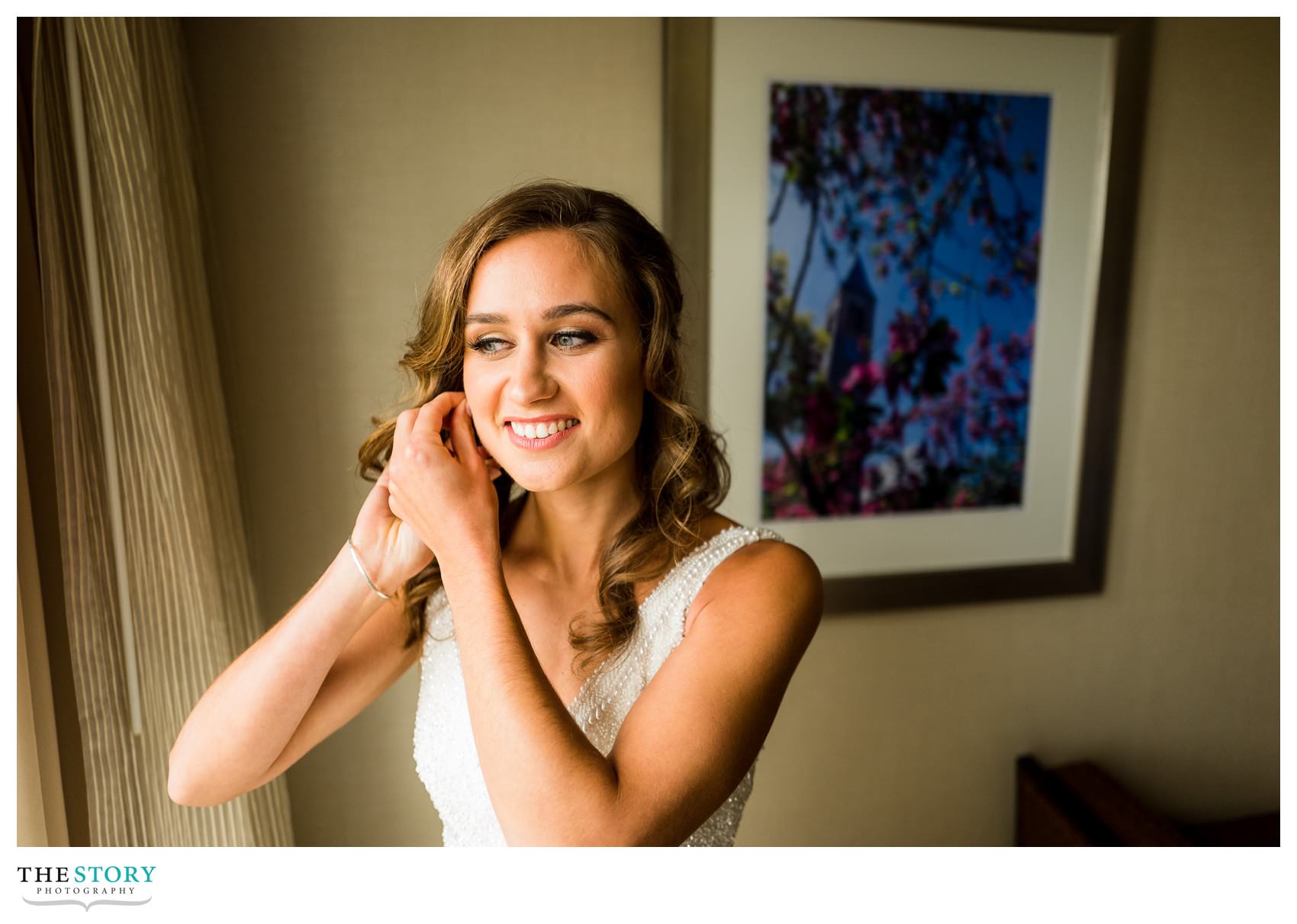 bride puts on earrings at Cornell University Statler Hotel