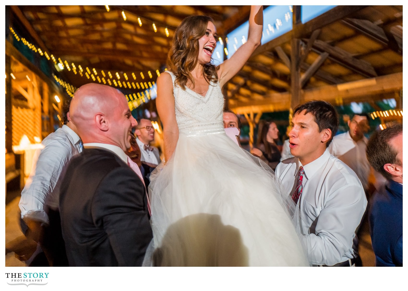 bride is lifted up during wedding hora at Ithaca Farmers Market wedding reception