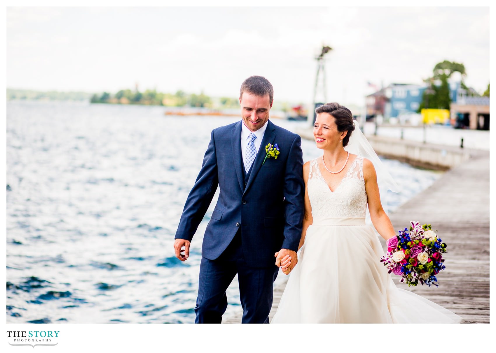 bride and groom walk by river in Clayton, NY