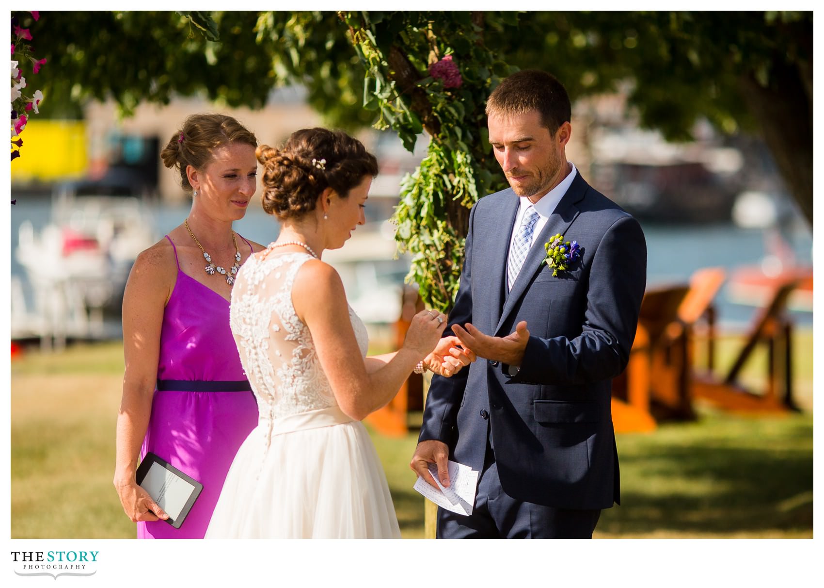 bride places ring on the groom's finger during outdoor wedding ceremony