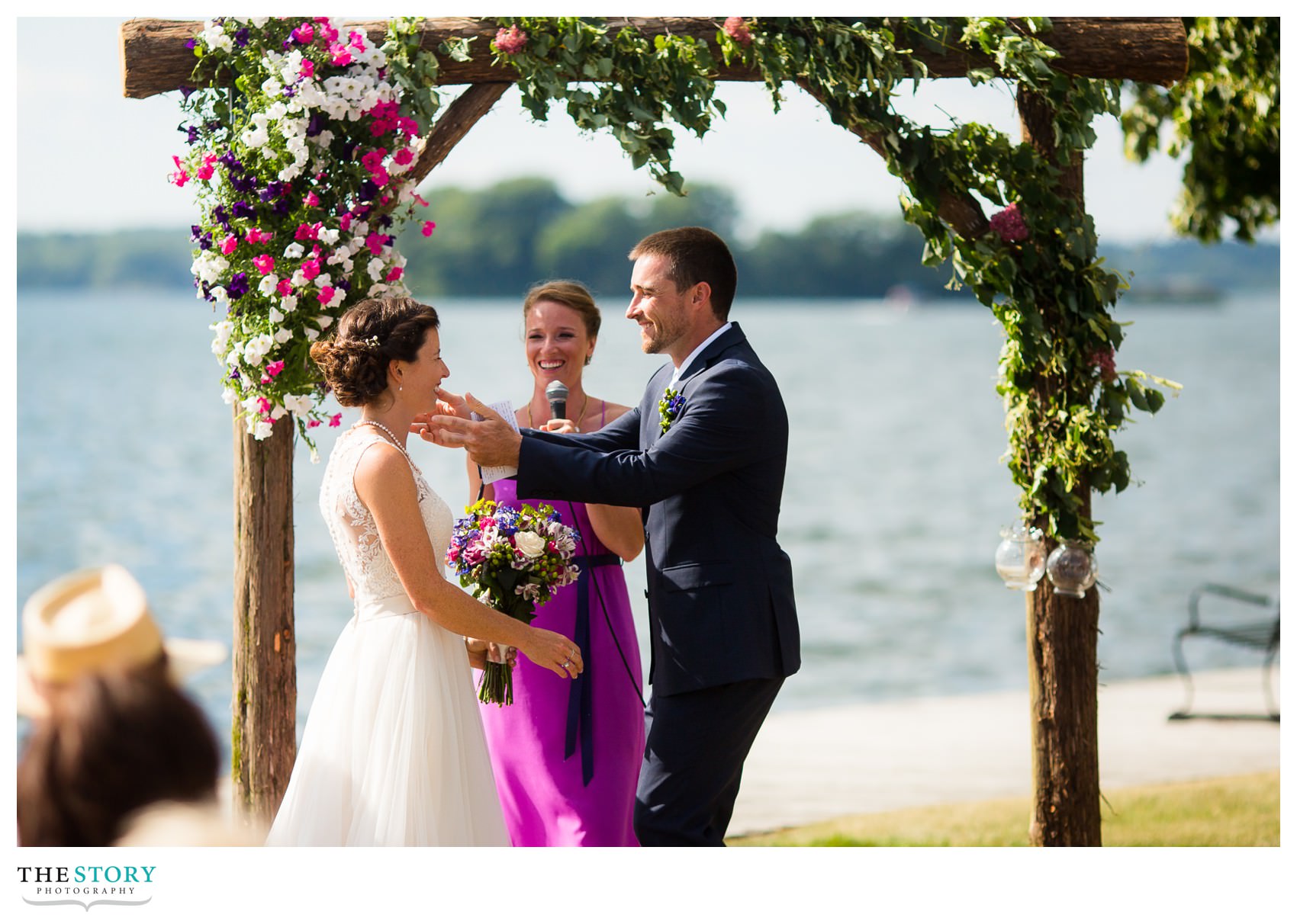 groom reaches for bride to give her the first kiss as husband and wife in Clayton, NY