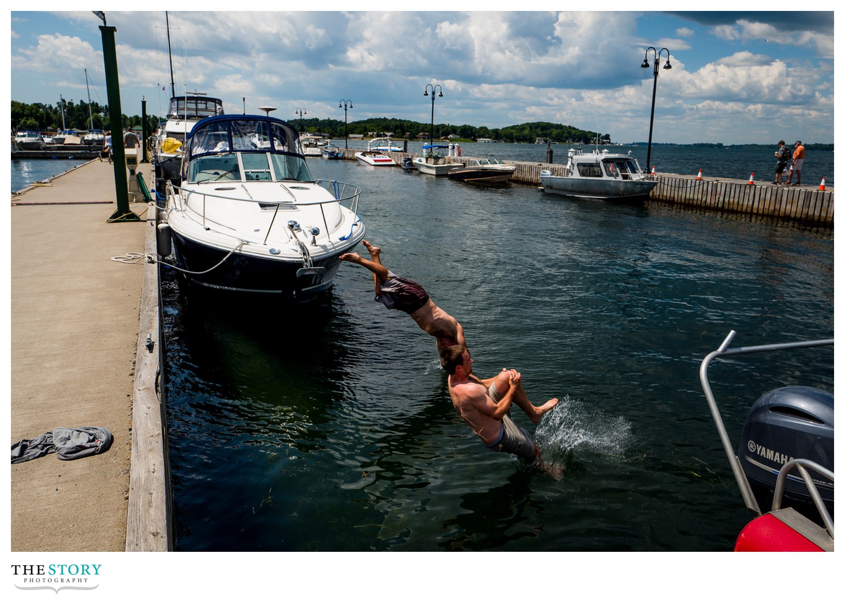 groom and groomsman jumping in river before wedding day in Clayton, NY