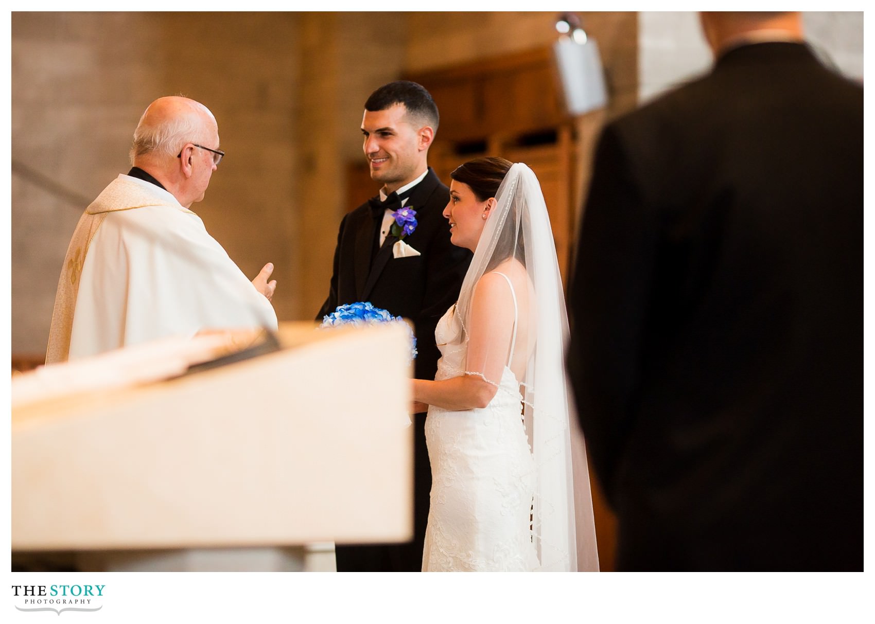 priest at Blessed Sacrament talks to bride and groom during wedding ceremony