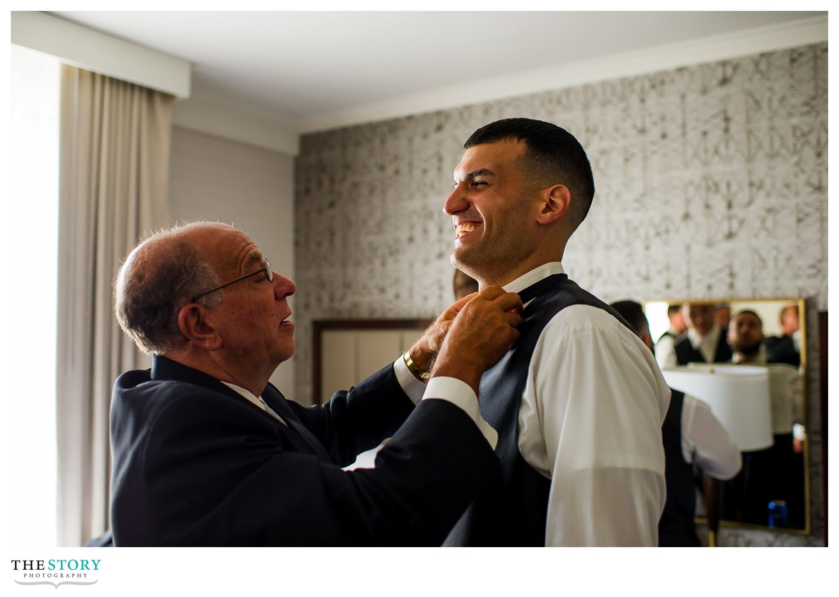father of bride helps groom with his tie at Marriott Syracuse Downtown wedding