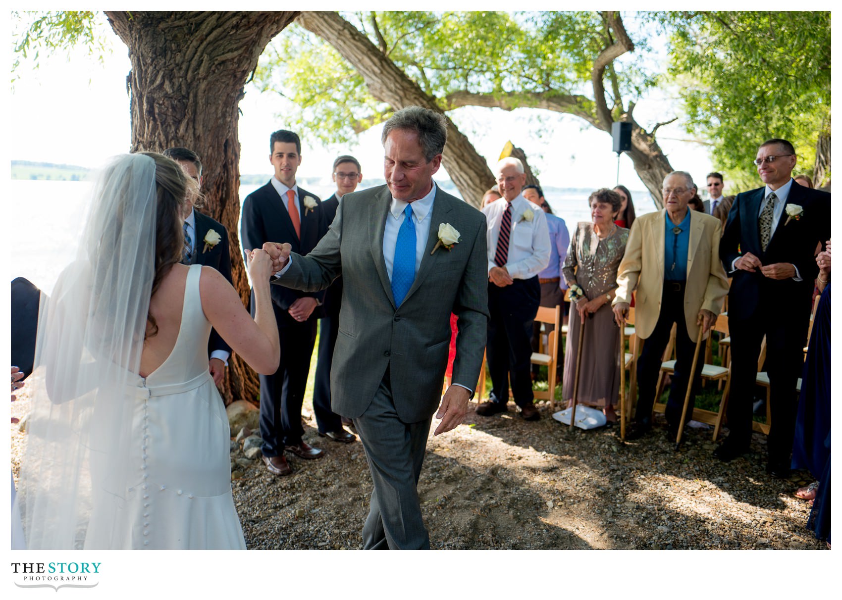 bride and father fist bump at lakeside wedding ceremony