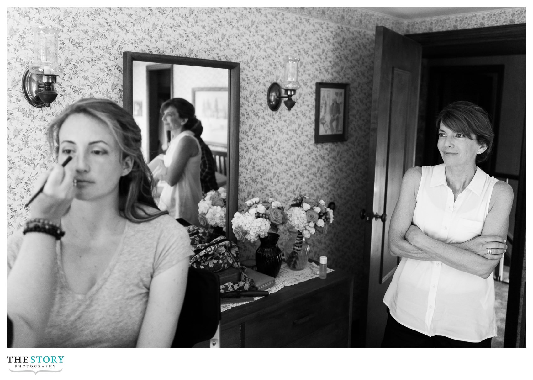 mother of the bride looks on while her daughter gets ready for her wedding day