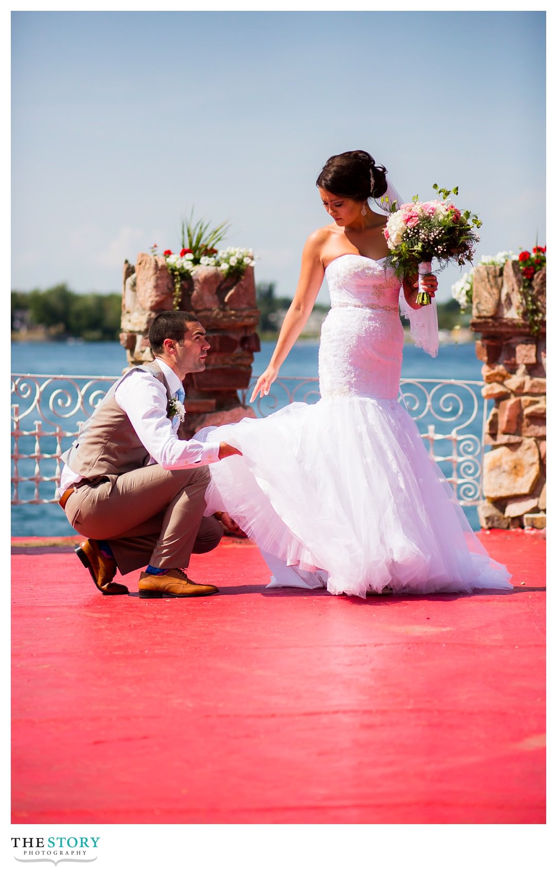 groom helping bride get ready for wedding day portrait