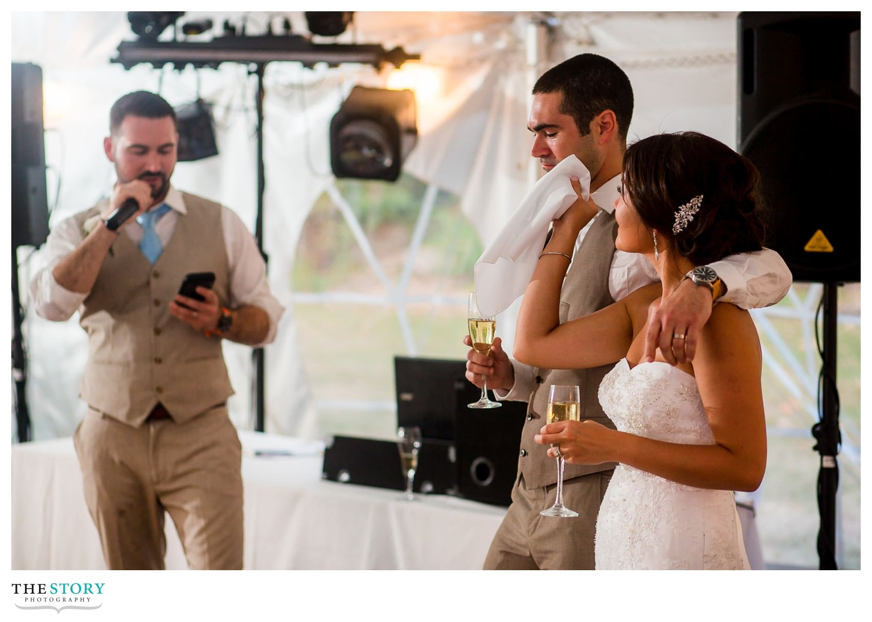 bride wipes a tear from the groom's face during the best man speach