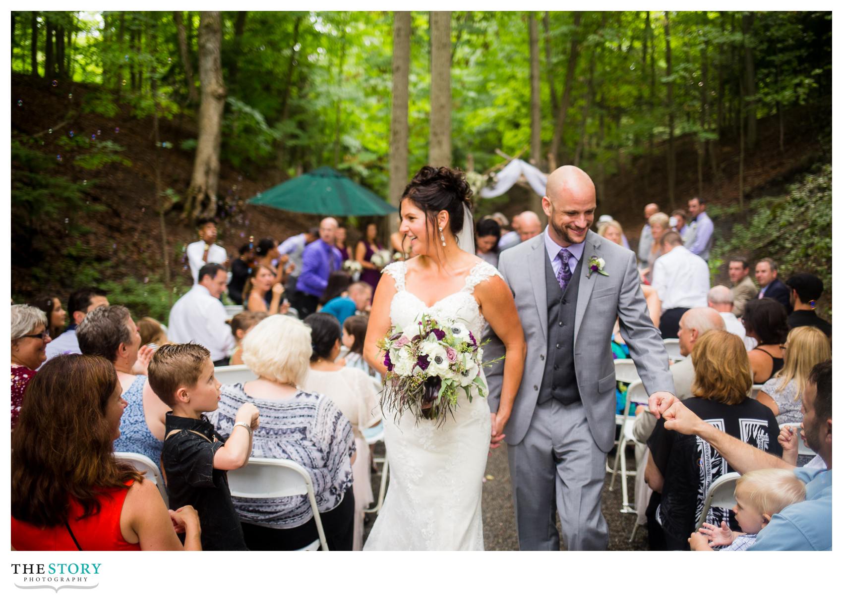 bride and groom celebrate while walking down aisle after wedding ceremony