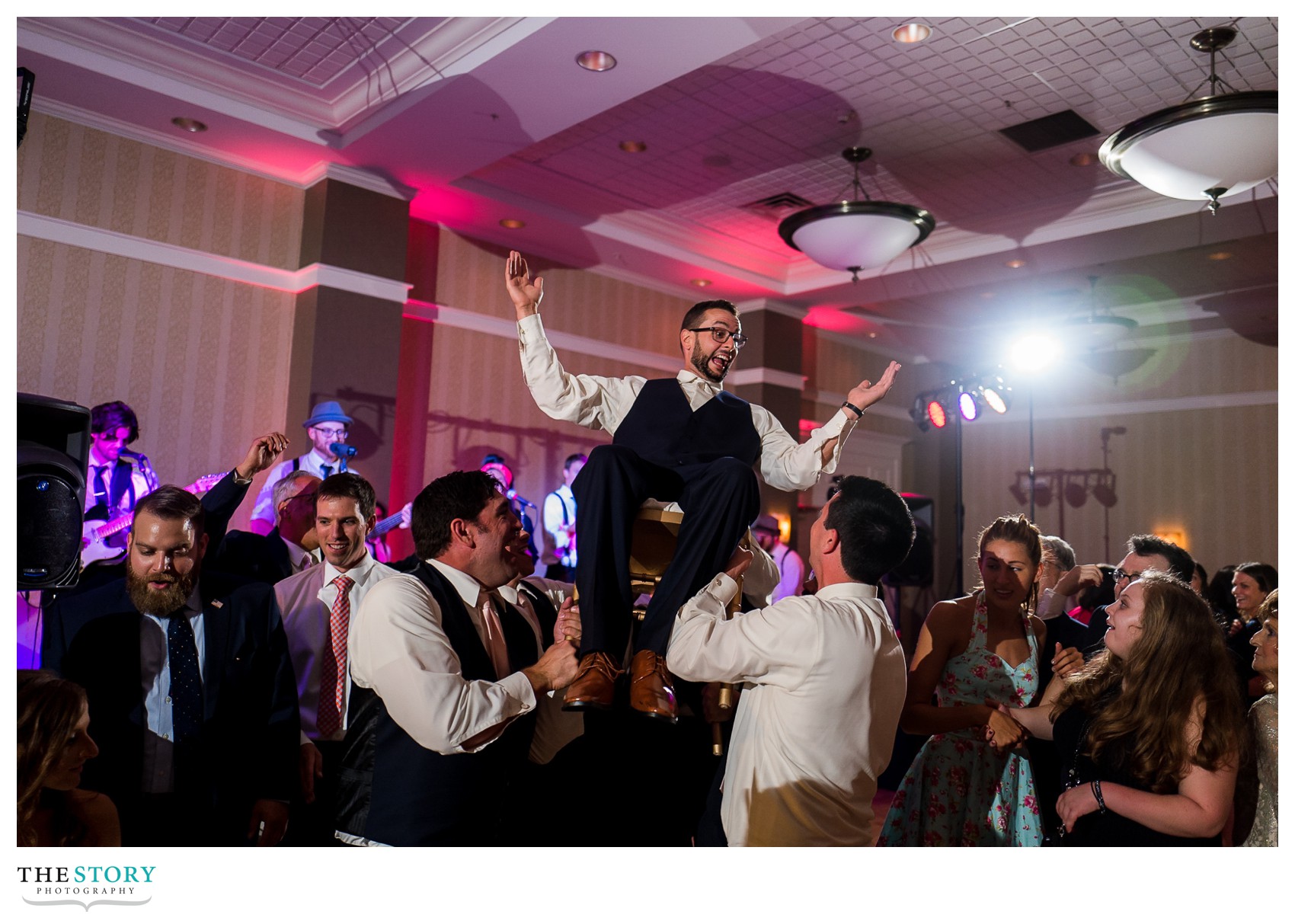 groom gets lifted on chair during wedding reception
