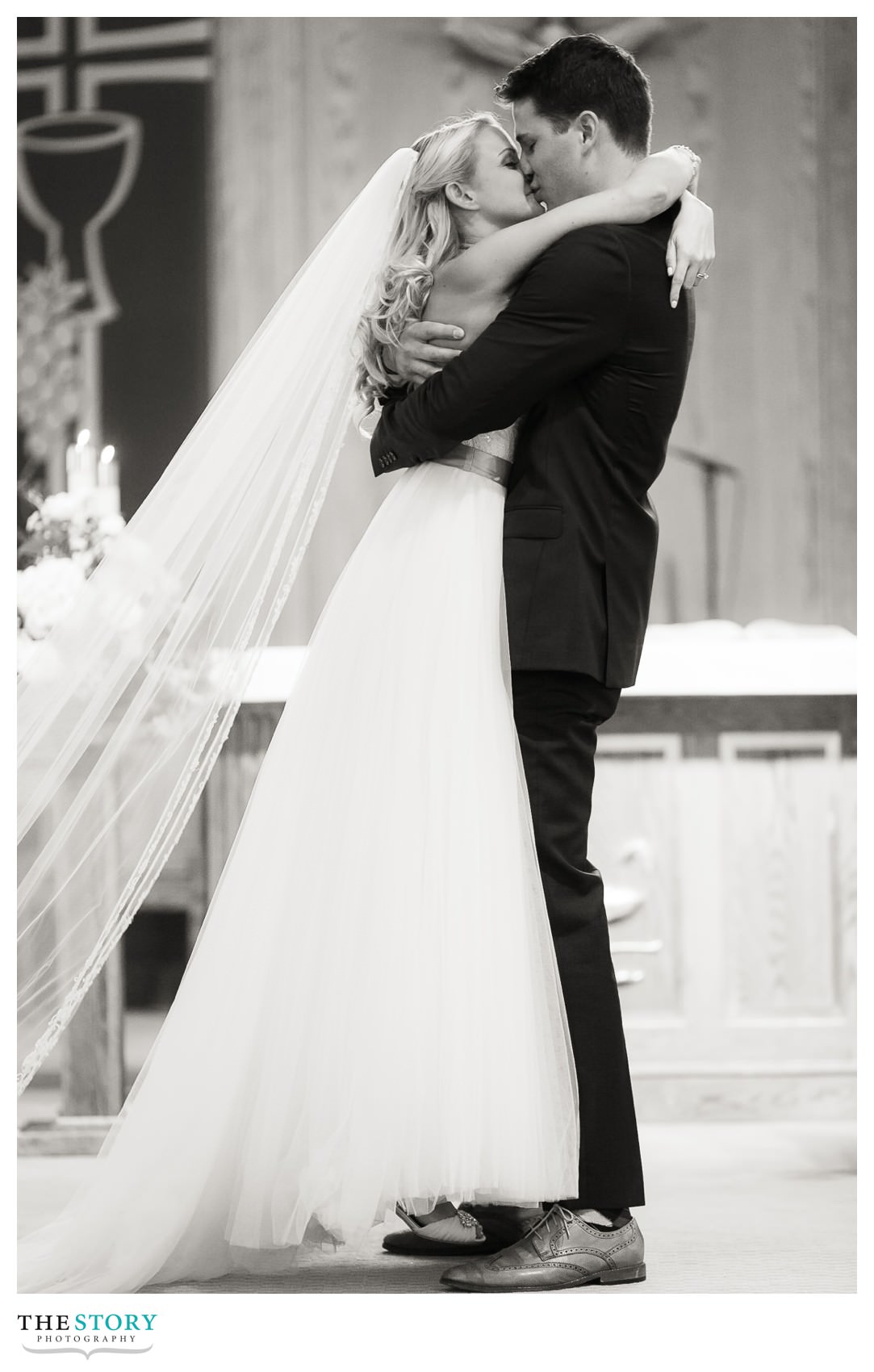 Groom lifts bride off of her feet during the first kiss!