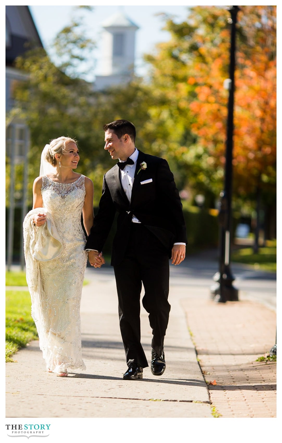 bride and groom walk down the street in Skaneateles