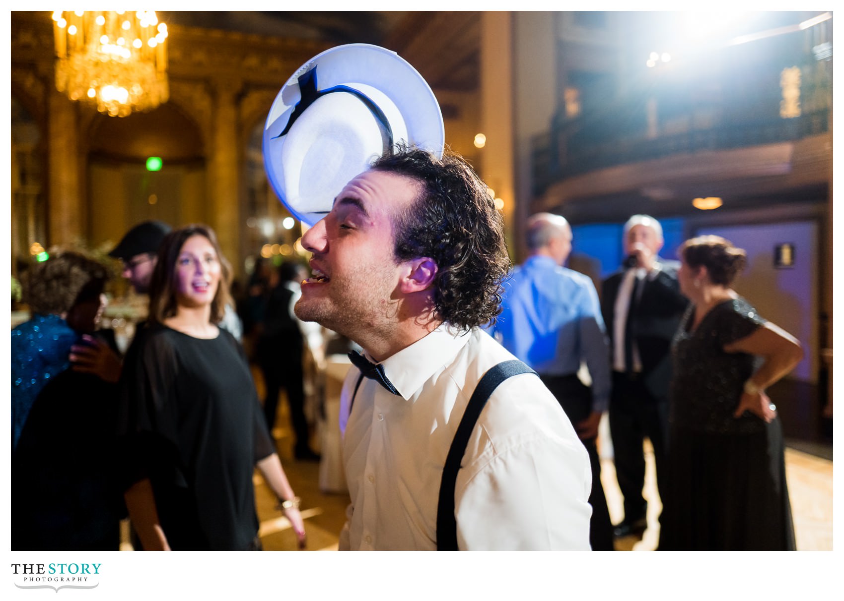 man attempts to catch a hat on his head at wedding reception