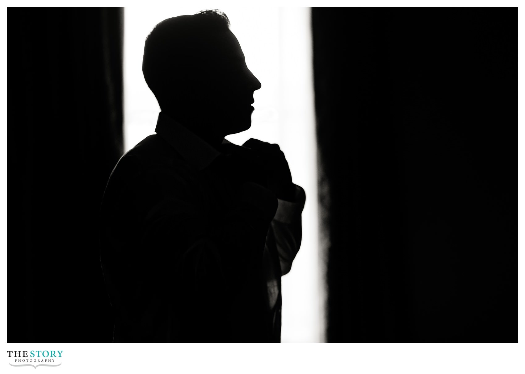 shillouette of groom getting ready in Hotel Syracuse suite