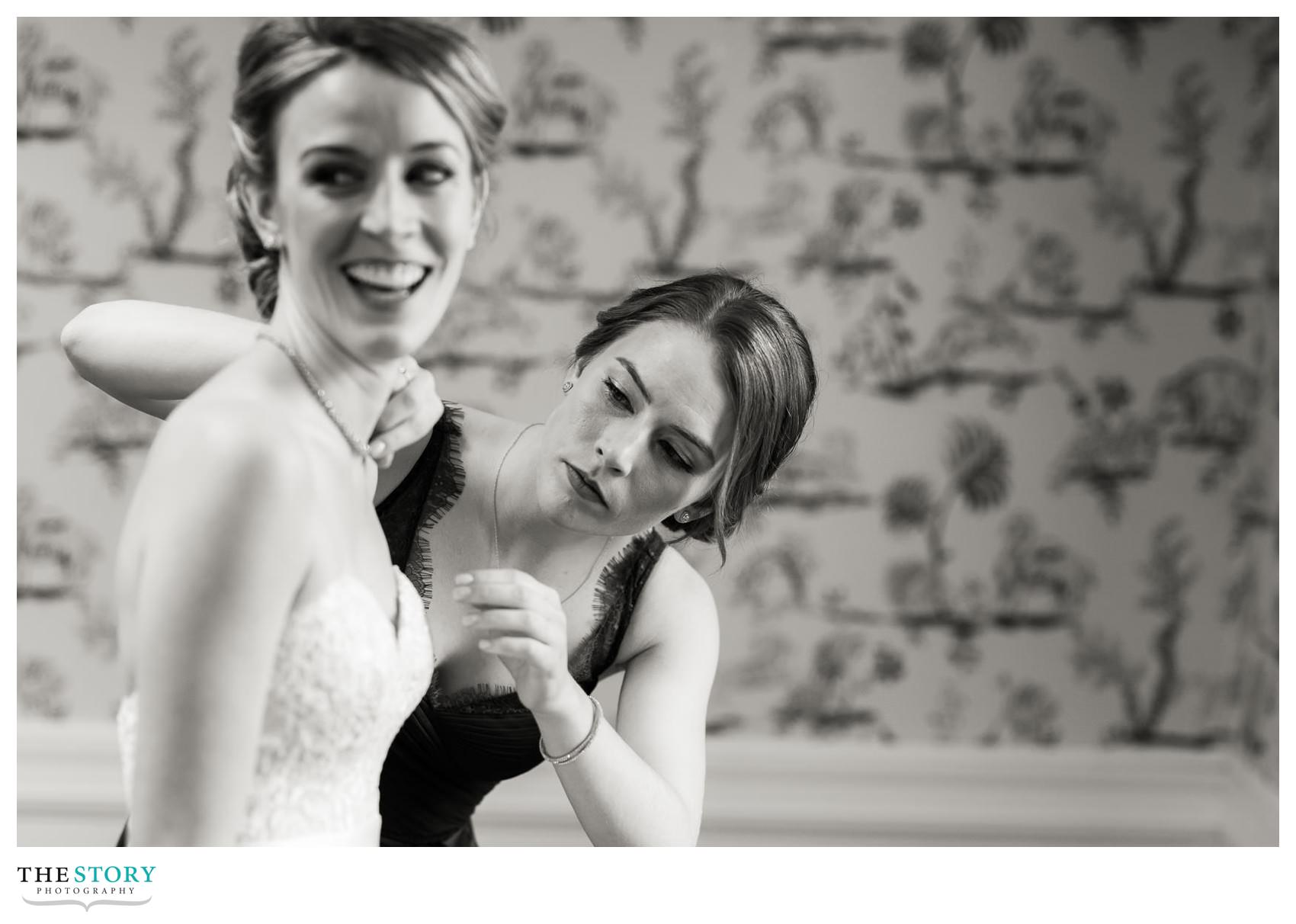 sister of bride makes sure that the necklace is perfect before the wedding
