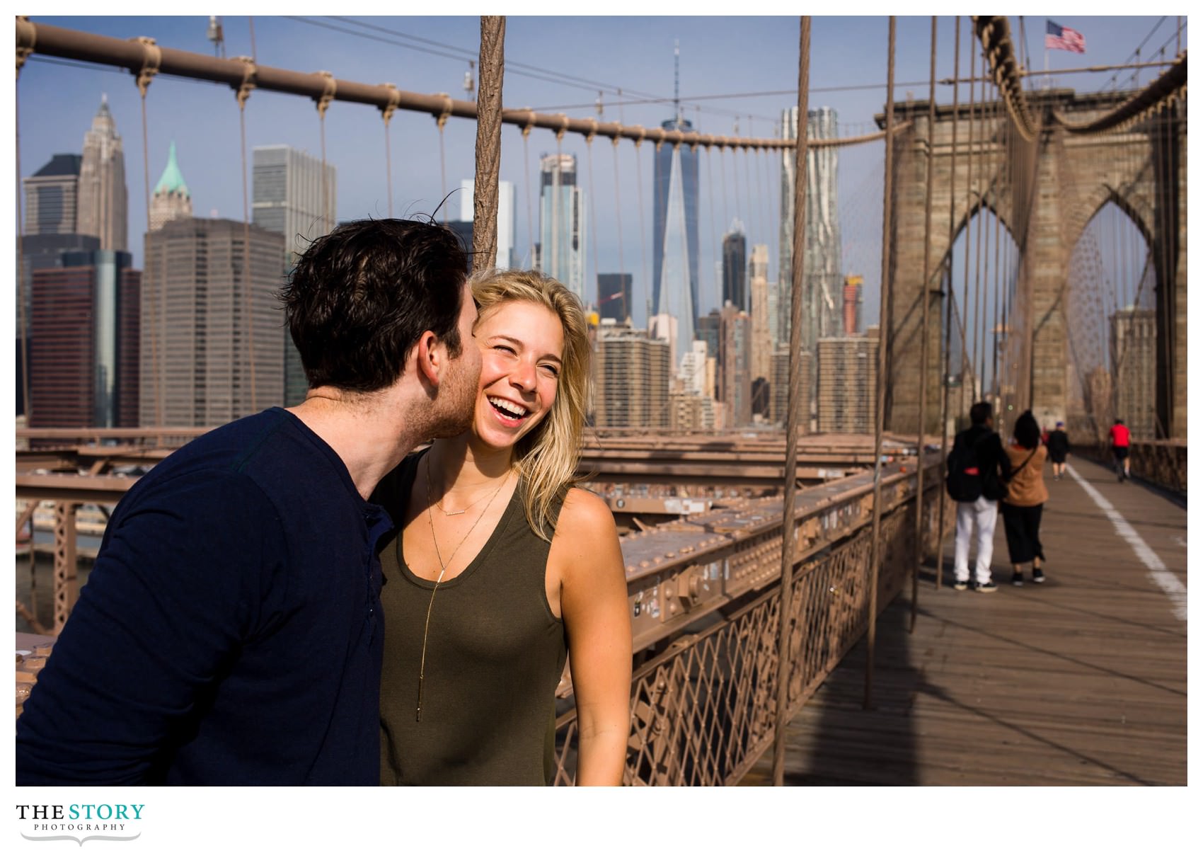 couple having fun on Brooklyn Bridge with Manhattan skyline in the background