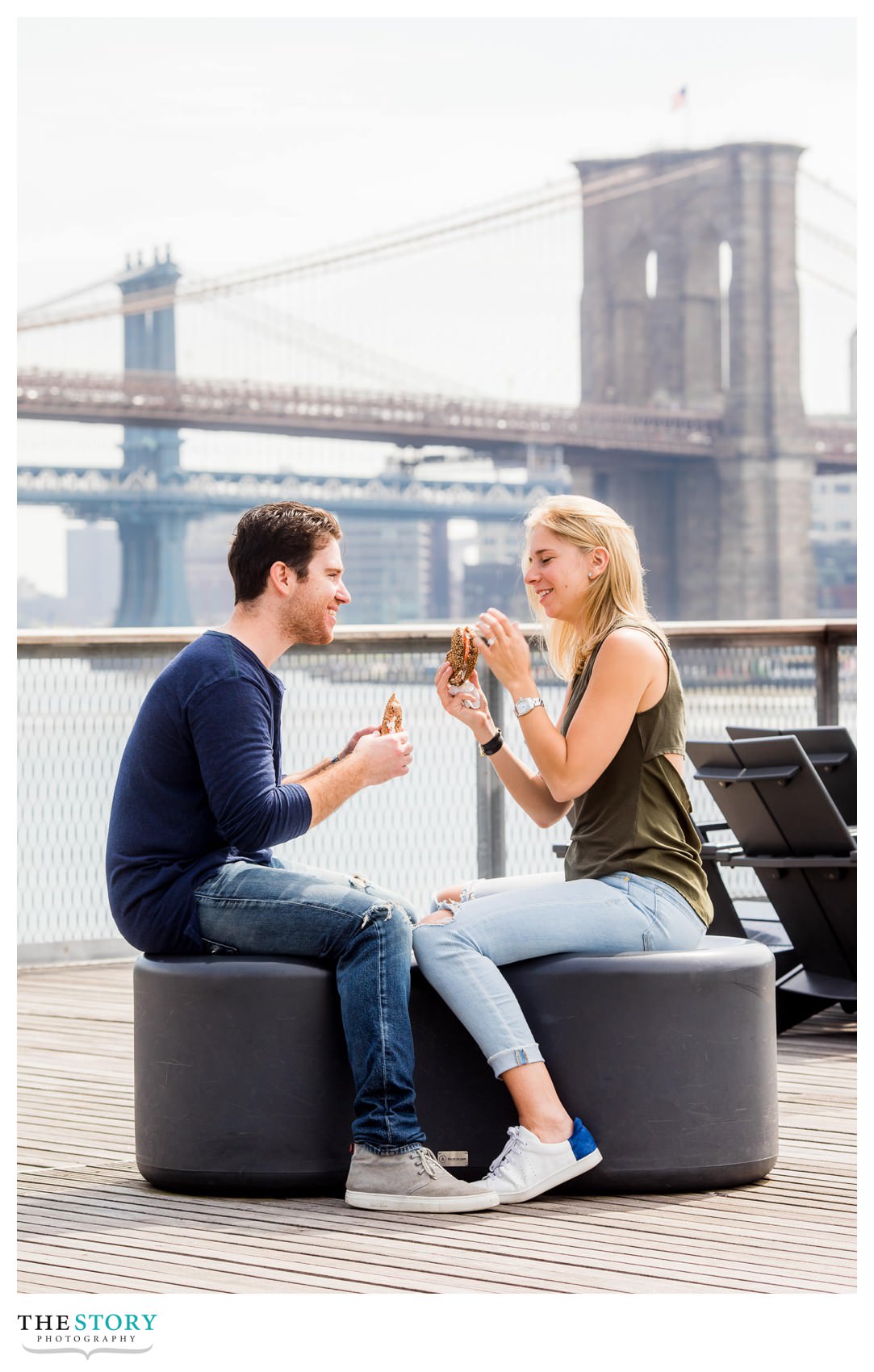 couple enjoying a breakfast bagel on the river with Brooklyn bridge in the background