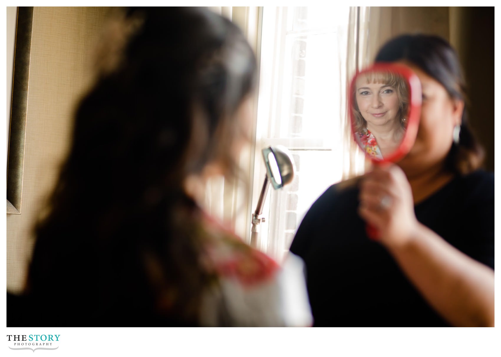 reflection of mother in mirror as bride looks at her makeup