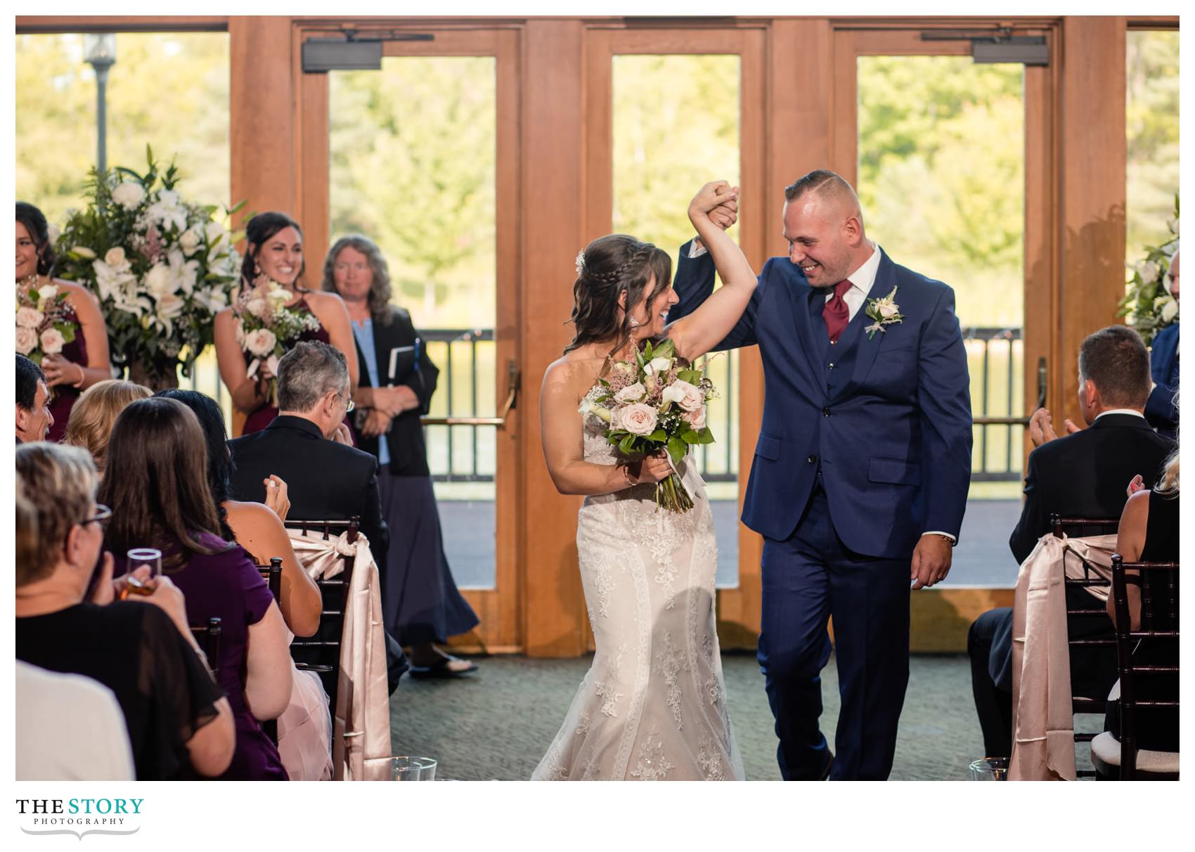 bride and groom raise hands in celebration at the end of the wedding ceremony