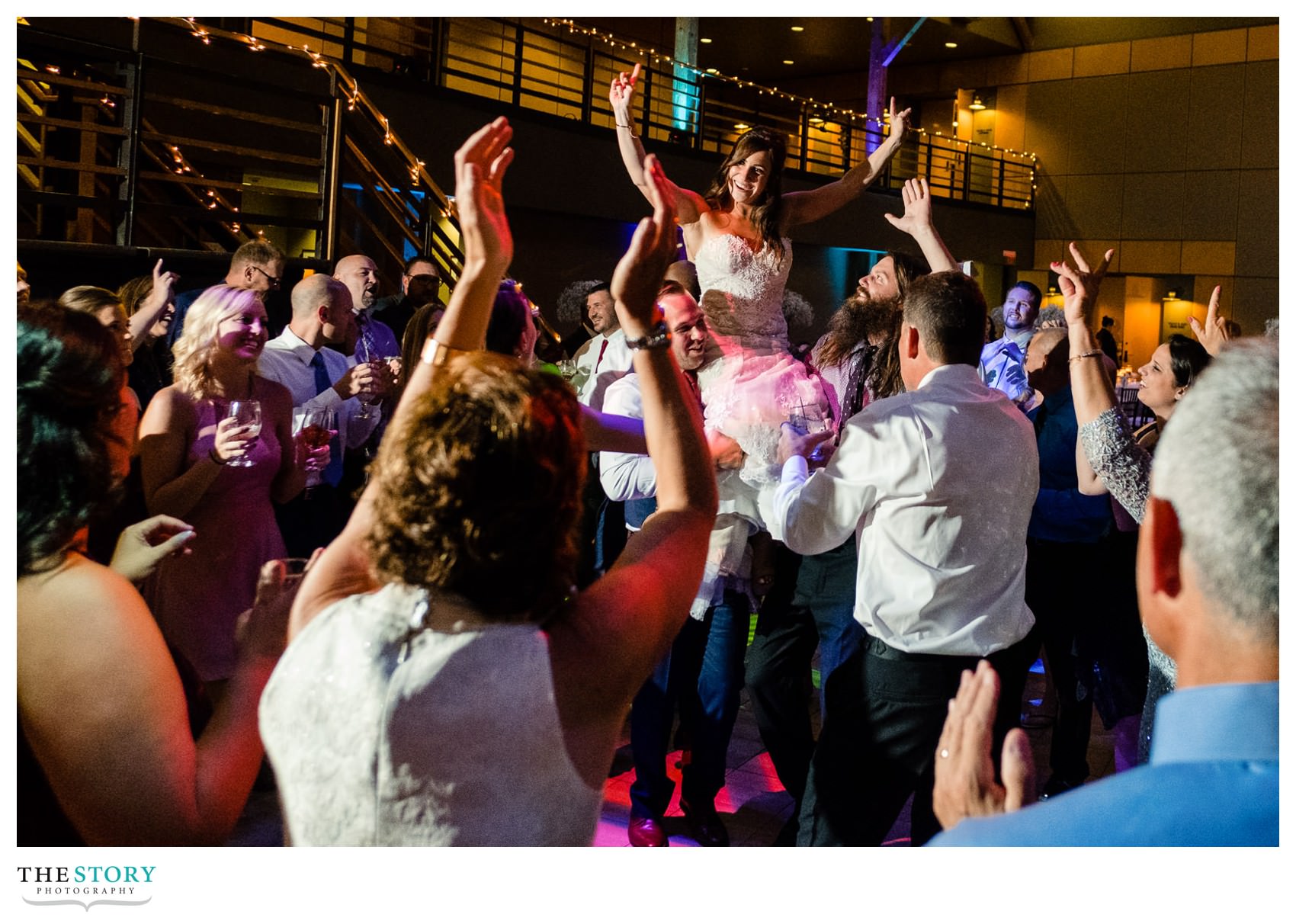 bride gets lifted up during the wedding reception party