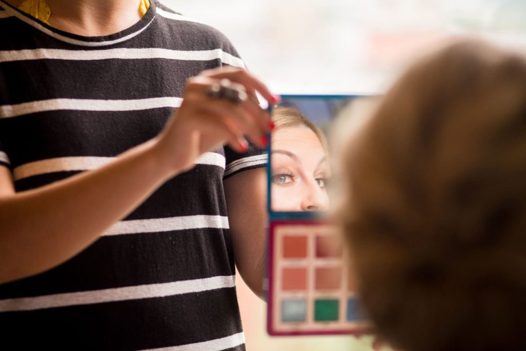 bride looking in mirror to check her wedding makeup