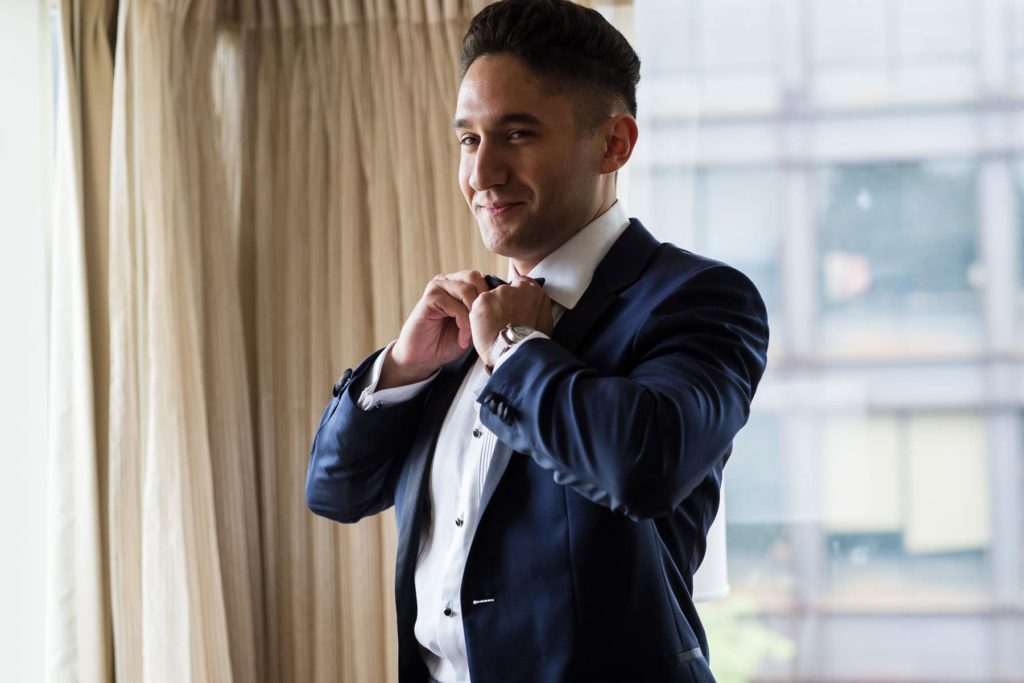 groom adjusts his tie before wedding