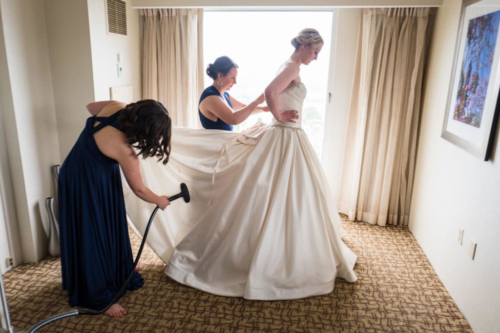 bride's dress getting steamed and buttoned