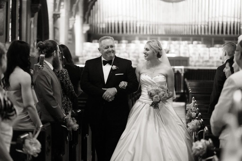 father of bride winks at a friend during wedding ceremony