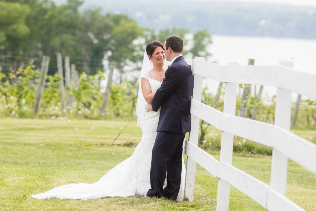happy bride and groom near white horse fence at vineyard wedding