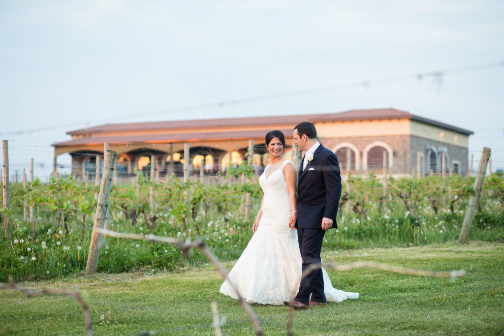 bride and groom walk through vineyard with Ventosa in the background
