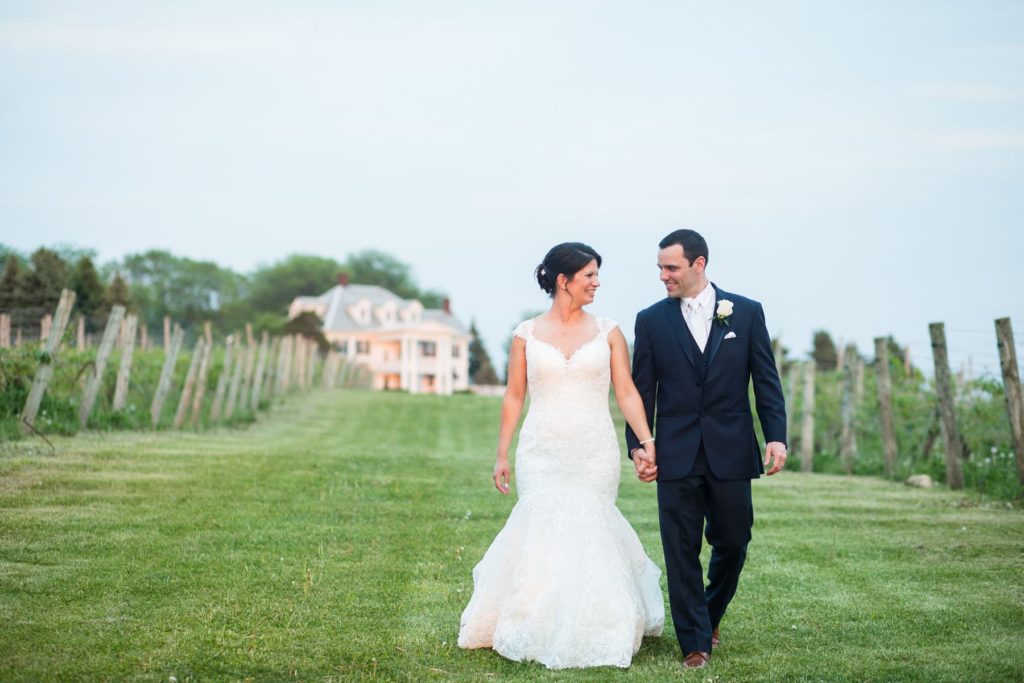 bride and groom walking through finger lakes vineyard on wedding day